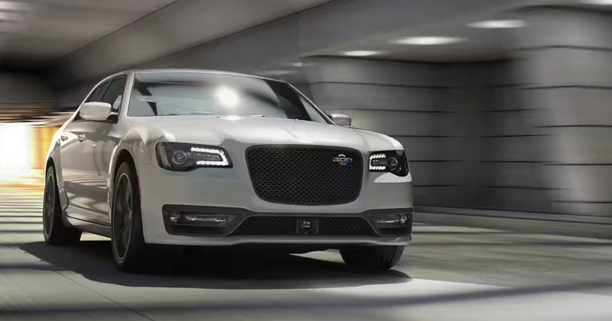 A sleek Chrysler 300 with a bold front grille and LED headlights speeds through a modern tunnel. The scene conveys power and elegance.